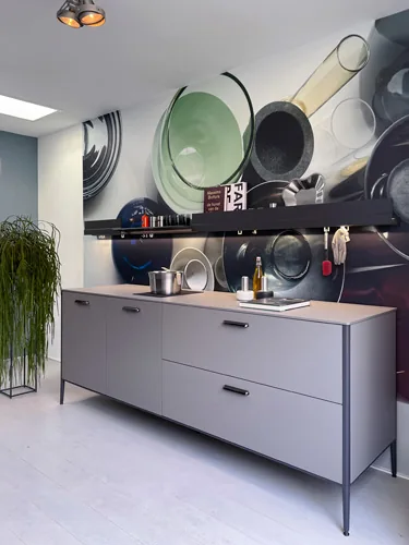 Grijs dressoir voor een wand met een muurschildering van pannen in de studio van Labor Coking