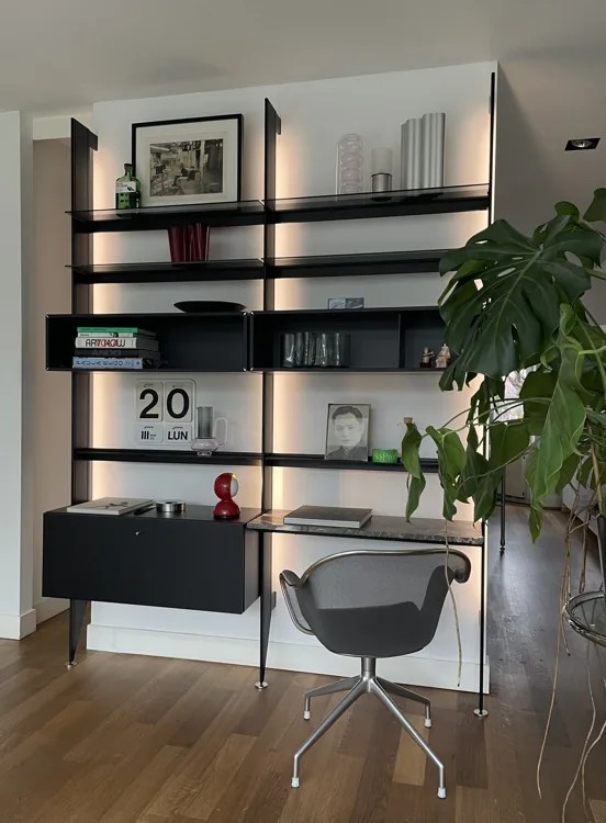 Zwart modulair wandsysteem met bureau, verlichting en bureaustoel